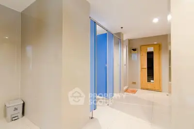 Modern bathroom with sauna and blue stall doors in a sleek real estate property.