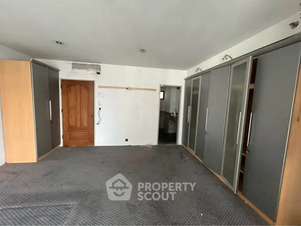 Spacious room with built-in wardrobes and wooden door, ideal for storage or conversion.