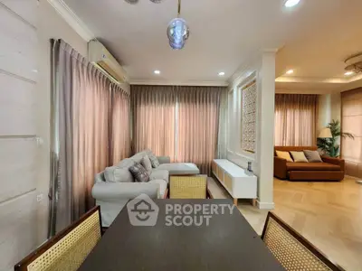Spacious living room with elegant decor and ample natural light, featuring a cozy seating area and modern dining space.