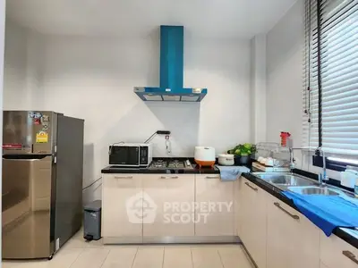 Modern kitchen with sleek appliances and ample counter space, featuring a gas stove and stainless steel fridge.