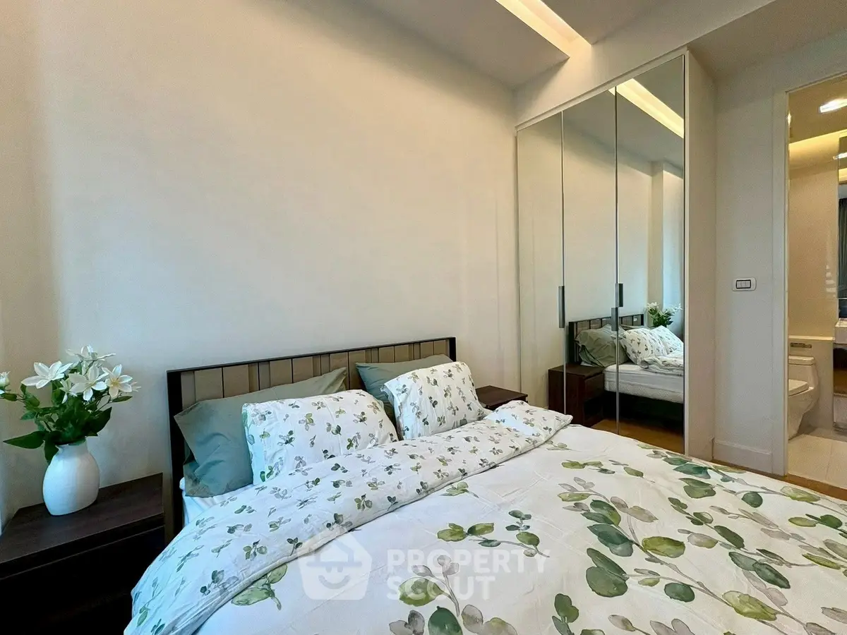Cozy bedroom with mirrored closet and floral bedding in modern apartment.