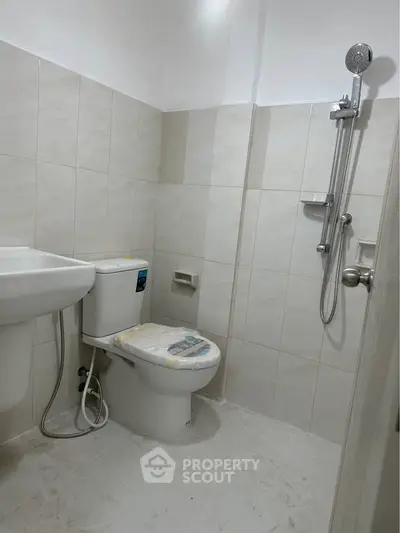 Modern bathroom with shower and toilet in a tiled setting.