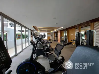 Spacious modern gym with state-of-the-art fitness equipment and large windows for natural light.