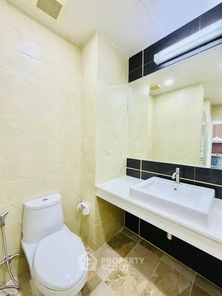 Modern bathroom with sleek design and large mirror, featuring a stylish sink and toilet.