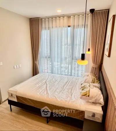 Modern bedroom with city view, featuring stylish lighting and elegant curtains.