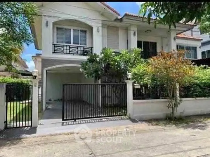 Charming two-story house with lush garden and gated entrance in a serene neighborhood.
