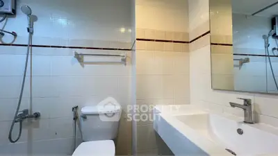 Modern bathroom with sleek fixtures and tiled walls, featuring a shower and a large mirror.