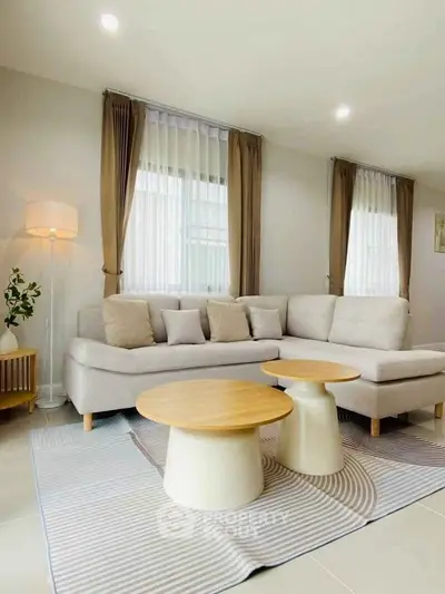 Modern living room with stylish beige sofa and chic round coffee tables.