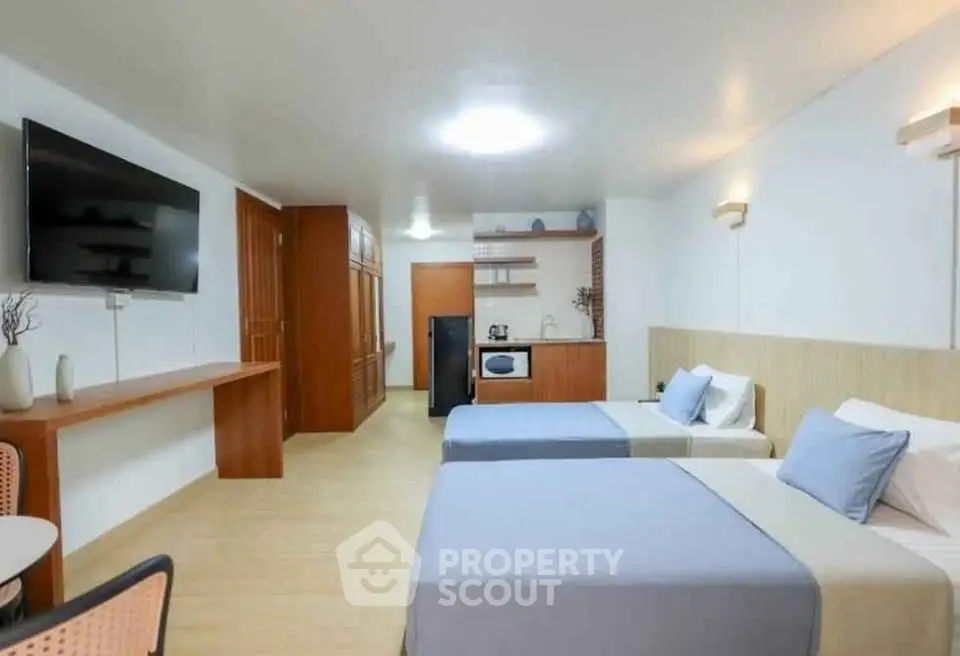 Spacious modern bedroom with twin beds and kitchenette, ideal for comfortable living.