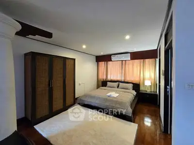 Spacious bedroom with elegant wooden flooring and modern furnishings