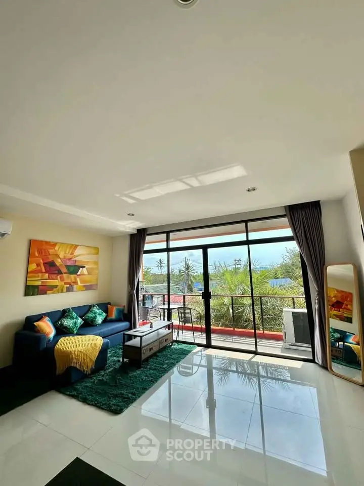 Spacious living room with large windows and balcony offering stunning views, perfect for relaxation.