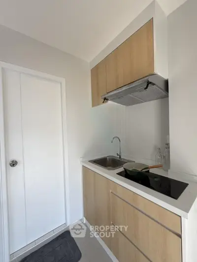 Modern compact kitchen with sleek wooden cabinets and electric stove