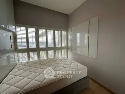 Modern bedroom with large windows and city view, featuring a comfortable mattress and sleek design.