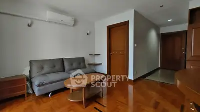 Spacious living room with wooden flooring and modern furniture in a cozy apartment.