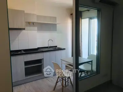 Modern compact kitchen with dining area and large window for natural light.