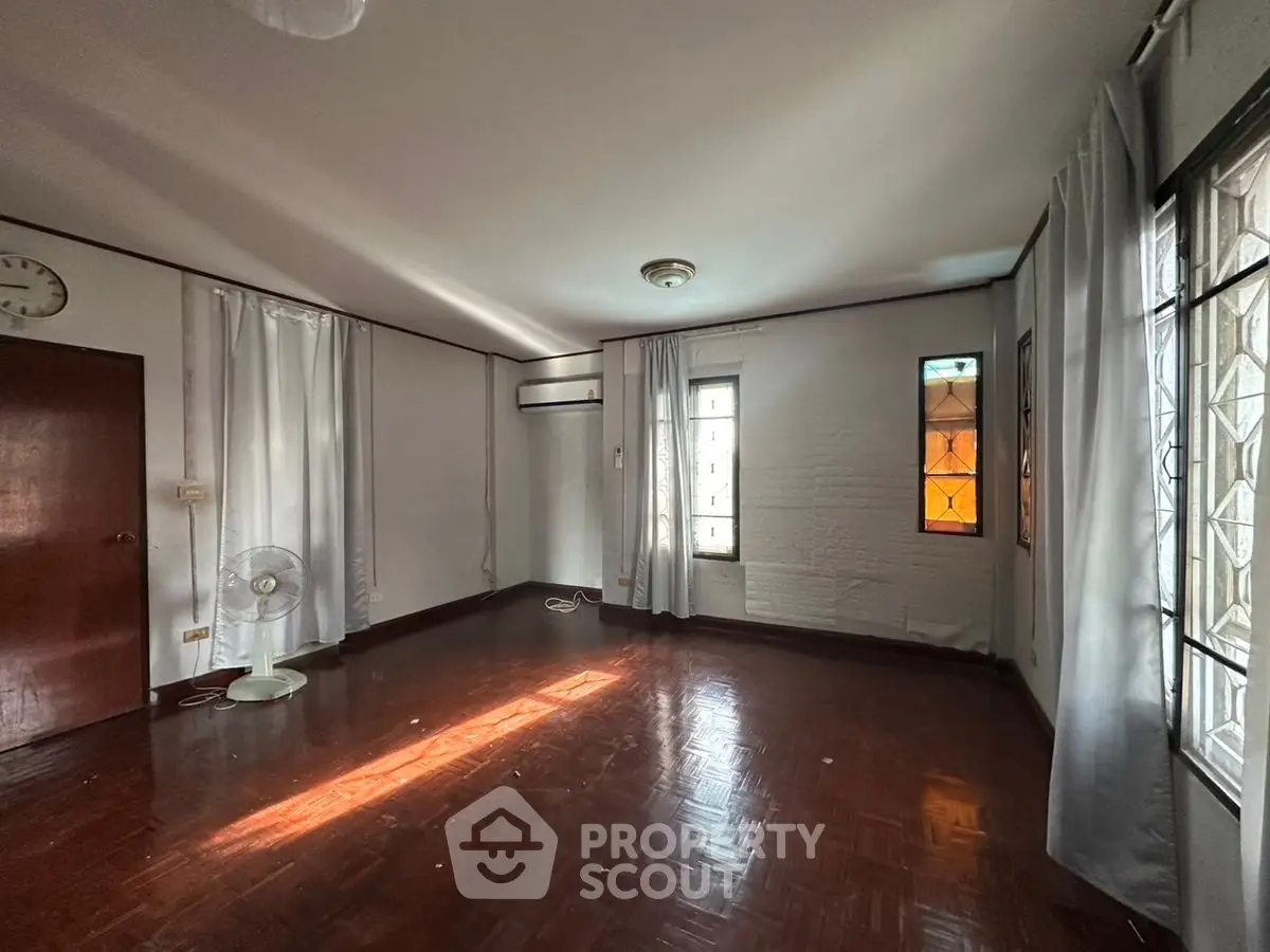 Spacious empty room with wooden floor and natural light