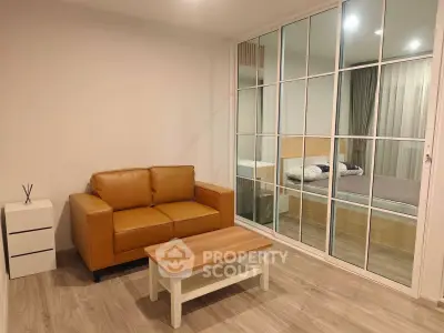 Modern living room with leather sofa and glass partition leading to bedroom