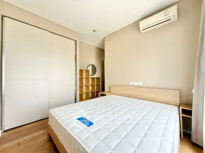 Modern bedroom with air conditioning and wooden flooring, featuring a spacious wardrobe and minimalist design.