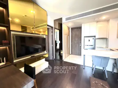 Modern living room with sleek design, featuring a large TV, stylish furniture, and an open kitchen layout.