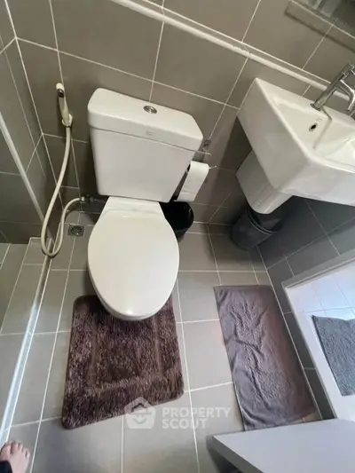 Modern bathroom with sleek fixtures and tiled flooring, featuring a toilet and sink.