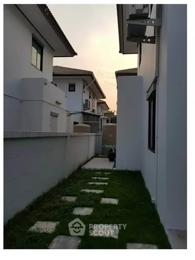 Charming suburban house exterior with lush green pathway and modern architecture at sunset.