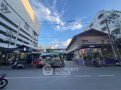 Street view of commercial buildings with vibrant signage and clear blue sky.