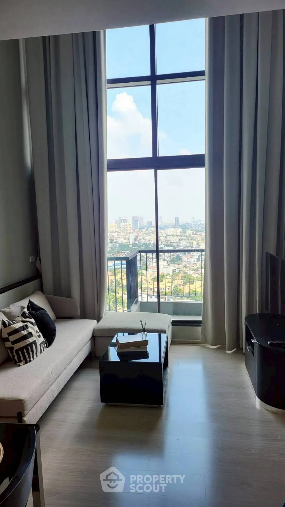 Luxurious living room with floor-to-ceiling windows offering stunning city views, modern furniture, and elegant decor.