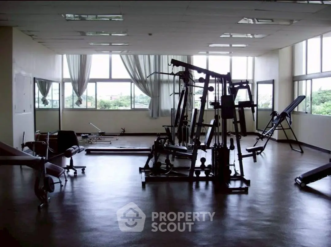 Spacious gym with modern equipment and large windows offering natural light and scenic views.