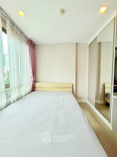 Bright bedroom with large windows and mirrored wardrobe in modern apartment