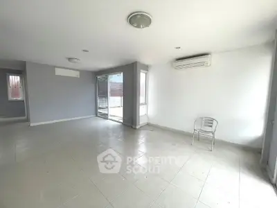 Spacious empty living room with tiled flooring and air conditioning, ready for customization.