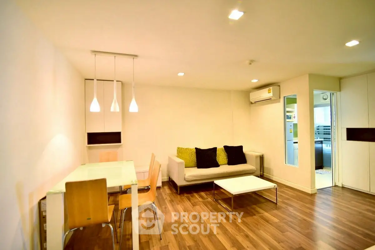 Modern living room with stylish furniture and wooden flooring, featuring a cozy dining area and ambient lighting.