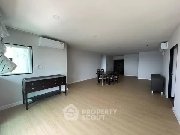 Spacious modern living room with wooden flooring and minimalist furniture.