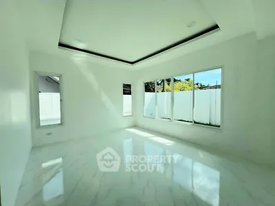Spacious sunlit room with large windows and elegant marble flooring in modern home.