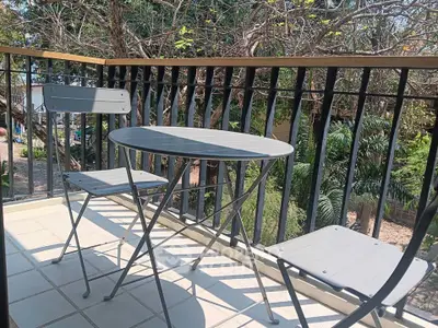Charming balcony with cozy seating and lush garden view, perfect for relaxation.