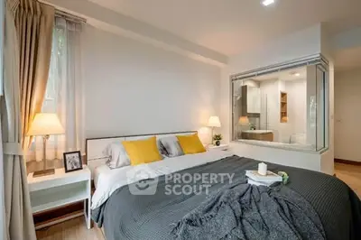 Modern bedroom with cozy lighting and large window, featuring a unique glass partition to the bathroom.