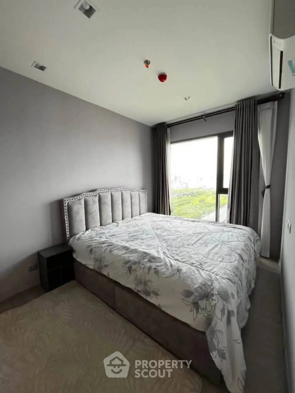 Modern bedroom with large window and stylish bed in a contemporary apartment.