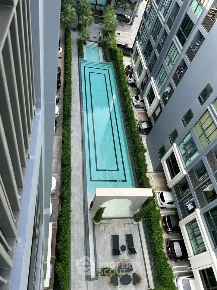 Stunning aerial view of modern apartment complex with luxurious swimming pool and lush greenery.