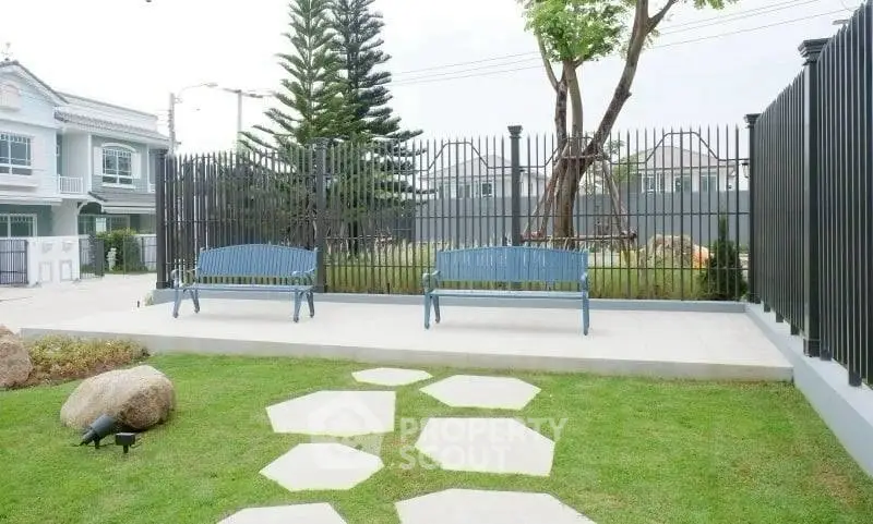Charming garden with benches and modern fence in a serene residential area.