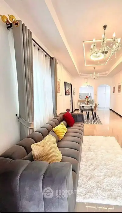Luxurious living room with plush sofa and elegant dining area, featuring modern chandeliers and stylish decor.