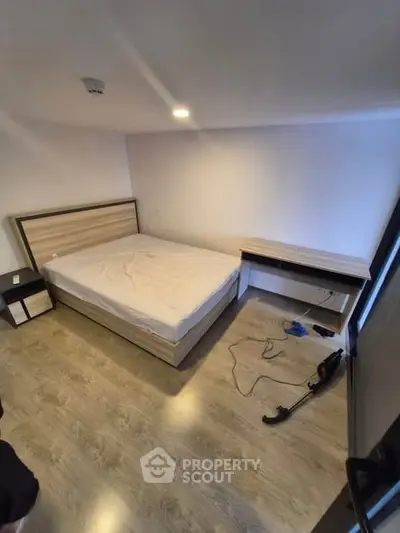 Spacious bedroom with modern wooden flooring and minimalist furniture design.