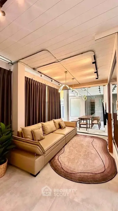 Modern living room with stylish decor and large windows, featuring a cozy sofa and elegant lighting.