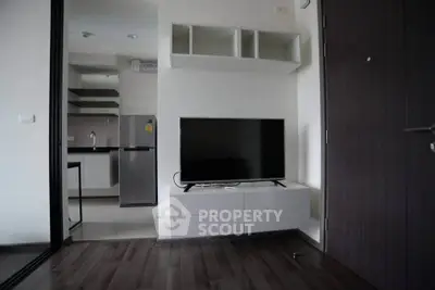 Modern apartment interior with sleek kitchen and stylish living area featuring a flat-screen TV.