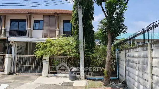 Charming townhouse with lush greenery and secure fencing in a peaceful neighborhood.