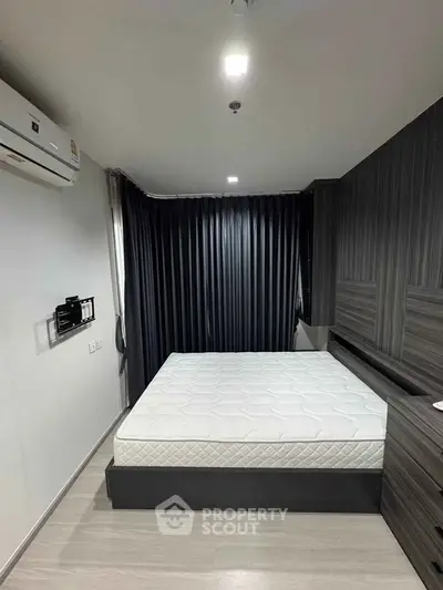 Modern bedroom with sleek design, featuring a comfortable bed and stylish dark curtains.