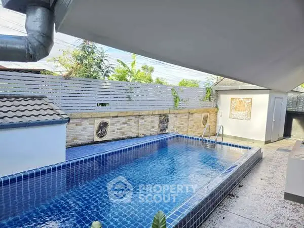Stunning private pool with modern tile design and lush greenery, perfect for relaxation and entertainment.