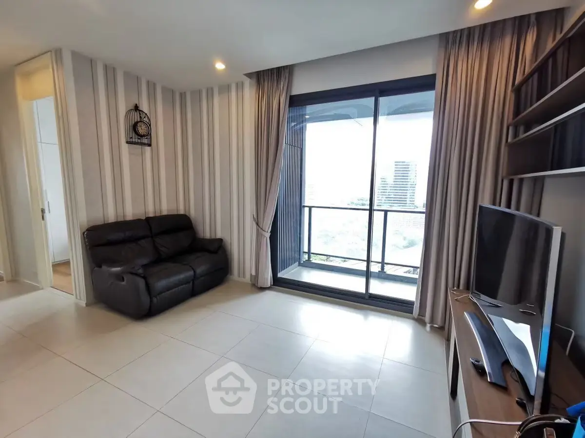 Modern living room with balcony view, featuring sleek furniture and stylish decor.