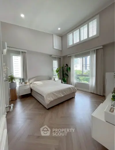 Spacious modern bedroom with large windows and elegant decor in a high-rise apartment.