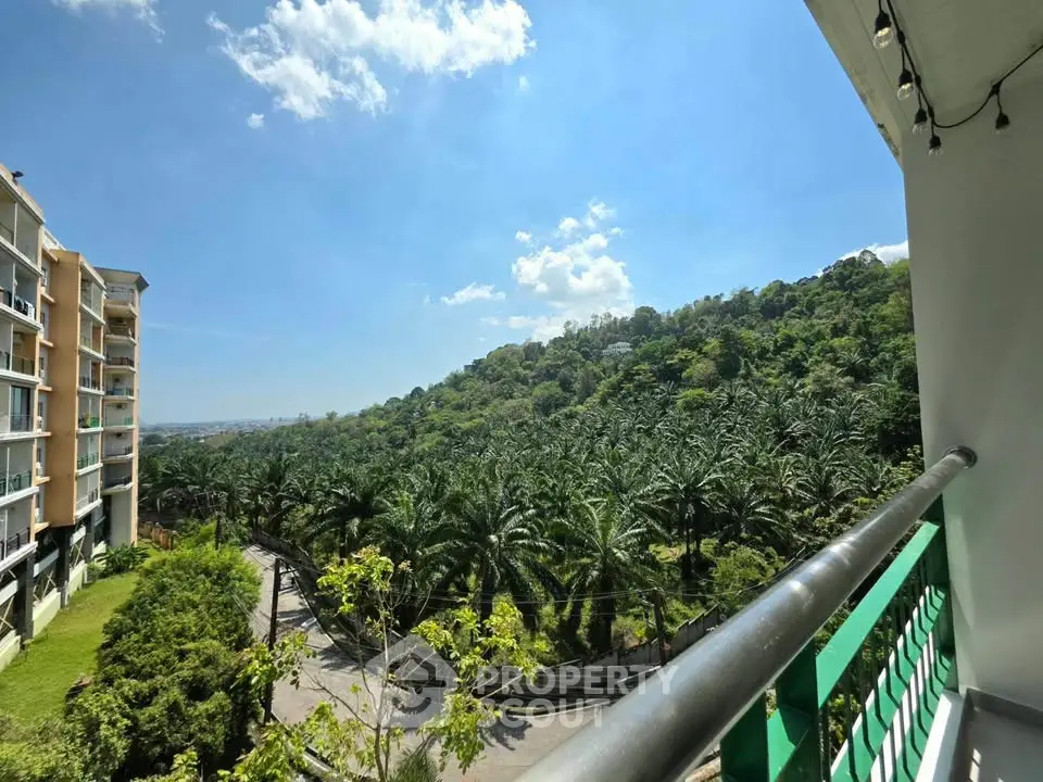 Stunning balcony view overlooking lush greenery and modern apartment building under a clear blue sky.