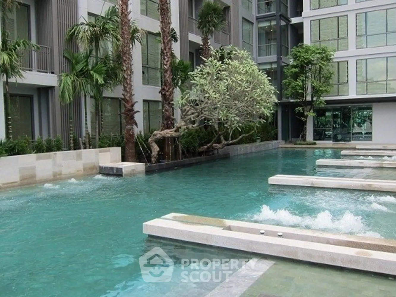 Luxurious modern apartment complex with stunning outdoor pool and lush greenery.