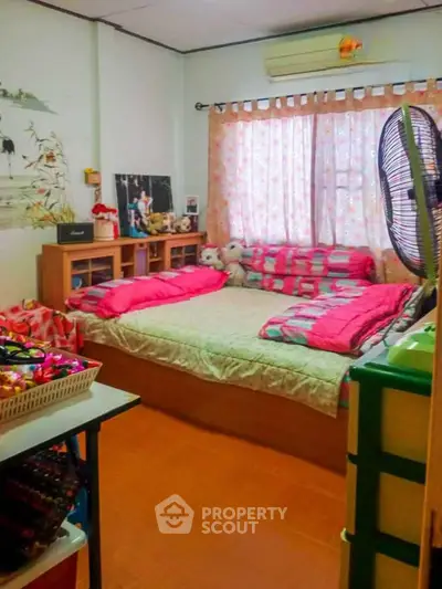 Cozy bedroom with colorful decor and natural light, ideal for a comfortable living space.